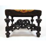 A 19th century ebonised continental stool, the floral needlework seat on carved legs and stretchers,