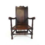 An early 18th century oak open armchair, the shaped cresting rail over the panel back and the