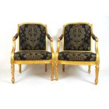 A pair of 18th century giltwood open armchairs upholstered in a black and gold floral fabric, the