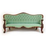 A Victorian walnut framed settee upholstered in a floral green button back fabric, the serpentine