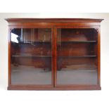 An early 19th century fiddleback mahogany wall hanging display cabinet, the cavetto cornice over two