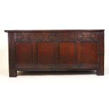 A late 17th century oak coffer, the four panel top lifting to reveal a vacant interior over the
