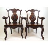 A pair of late 19th century teak Anglo-Chinese open arm chairs with profusely carved frame having