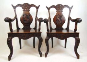 A pair of late 19th century teak Anglo-Chinese open arm chairs with profusely carved frame having