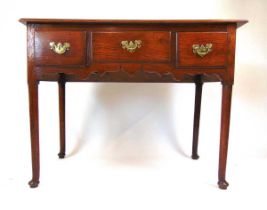 An 18th century oak and elm lowboy, the moulded top over three drawers and a shaped frieze on