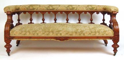 A late 19th century walnut settee upholstered in a floral patterned green fabric, the spindle back