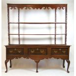 A mid 18th century oak dresser, the plate rack with shaped frieze on the base with three drawers