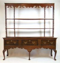 A mid 18th century oak dresser, the plate rack with shaped frieze on the base with three drawers