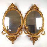 A pair of 18th century and later giltwood mirrors, the oval plates surmounted by a carved shell
