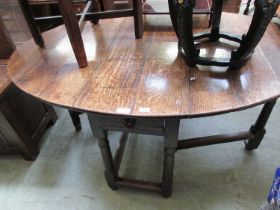 A 17th century oak gate leg table, the oval drop leaf top supported on a single gate action over