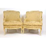A pair of reproduction cream and parcel gilt French style armchairs upholstered in a floral