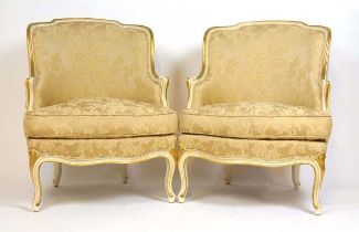 A pair of reproduction cream and parcel gilt French style armchairs upholstered in a floral