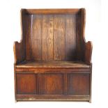 An early 20th century oak box settle, the back over lift up seat revealing a vacant interior above