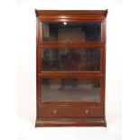 An early 20th century walnut sectional bookcase, comprising of plinth, base section with drawer