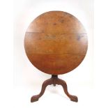 An early 19th century oak tilt top tripod table, the circular top on turned column and three legs,