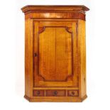 An 18th century oak and mahogany wall hanging corner cupboard, the cornice over single panel door