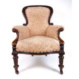 A Victorian walnut framed nursing chair upholstered in a floral patterned fabric, the carved