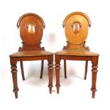 A pair of 19th century oak hall chairs, the oval back supported on carved C-scrolls on turned