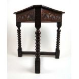 A late 17th century and later oak side table, the triangular lift up top over lunette carved