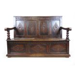 An 18th century and later oak settle, the diamond carved four panel back above the lift up lid
