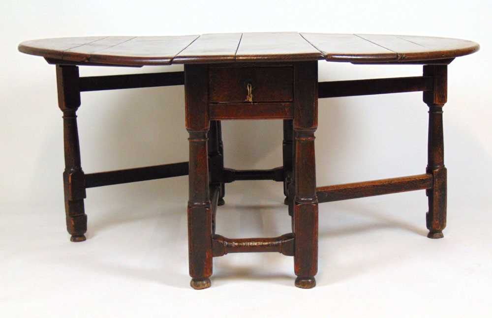 A late 17th/early 18th century oak gate leg dining table, the drop leaf top supported on a single