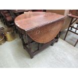 An early 18th century oak drop leaf table, the oval top supported on a single gate action over a