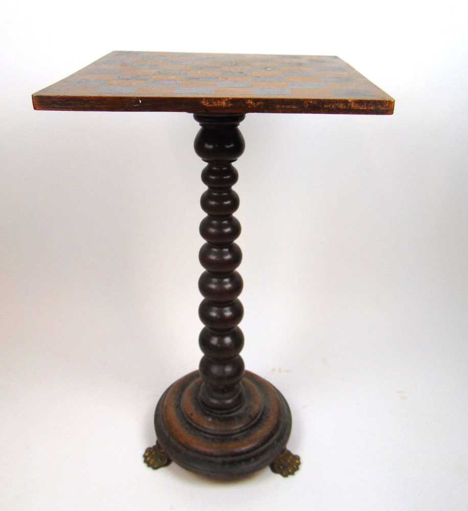 An early 19th century oak games table, the revolving top on a tapering bobbin column and circular