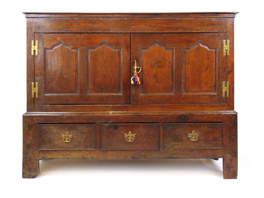 An early 18th century and later oak cabinet, the top over two twin arch top field panel doors