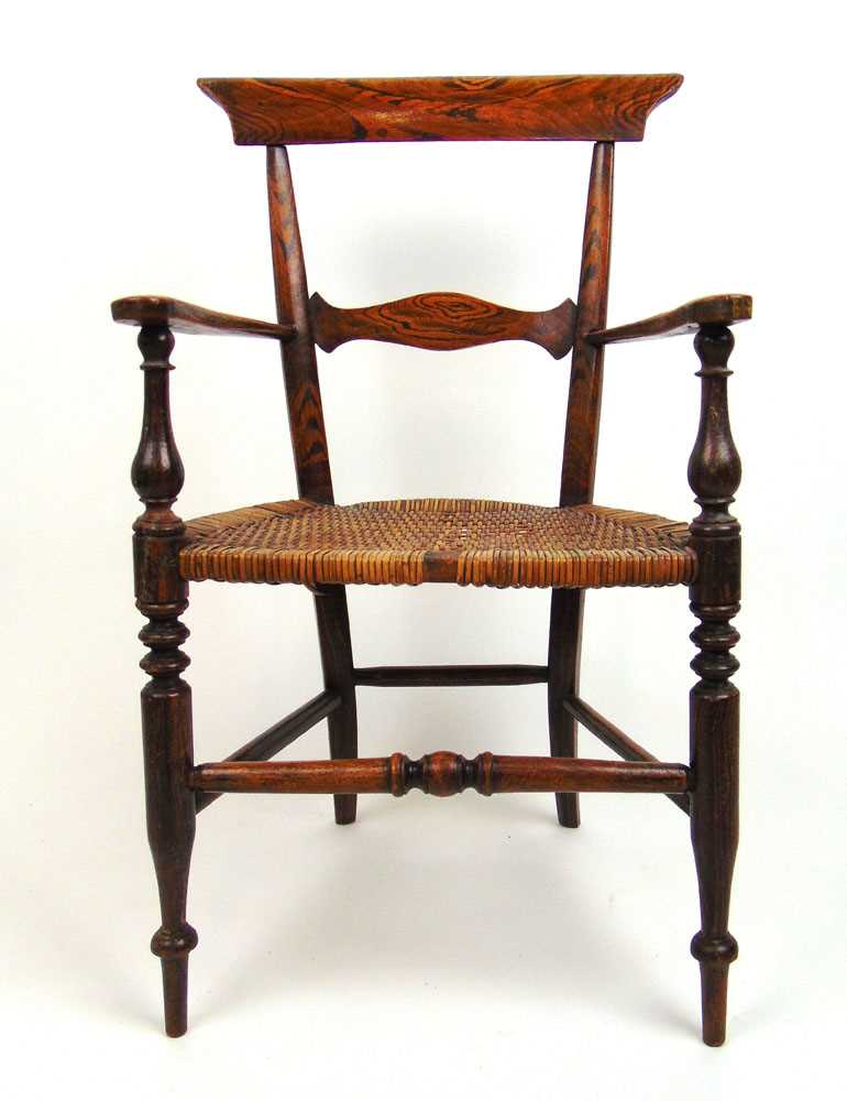An early 19th century simulated rosewood childs armchair, the caned seat on turned legs and