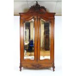 A late 19th century French walnut armoire, the Rococo carved domed pediment over two bevelled mirror