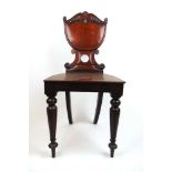 A Victorian mahogany hall chair, the carved shield back over the solid seat on turned and carved