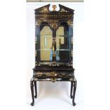 A 20th century Chinese black lacquer display cabinet, the broken arch pediment over two glazed doors