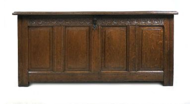 A George III oak four panel blanket box, the hinged top with recessed panels, above a running carved