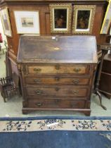 A George III oak bureau, the fall front with brass escutcheon above an inlaid marquetry conch shell,