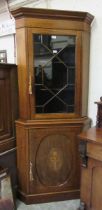 An Edwardian inlaid mahogany double corner cupboard, the upper section with astragal glazed door