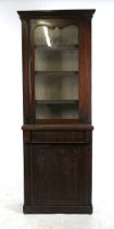 A narrow Victorian mahogany bookcase on cupboard, the glazed door enclosing fixed shelves, above a