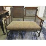 An early 20th century walnut framed two seat settee with cane back and sides