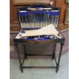 An early 20th century oak cutlery table containing silver plated flatware