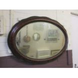 An early 20th century wood effect oval bevel glass mirror