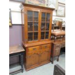 A modern small scale oak bookcase, two glazed doors over base with two drawers and two field panel