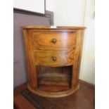 An Indonesian hardwood oval bedside cupboard, two drawers over open storage