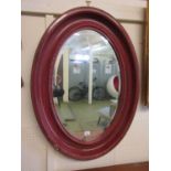 A red framed oval bevel glass mirror
