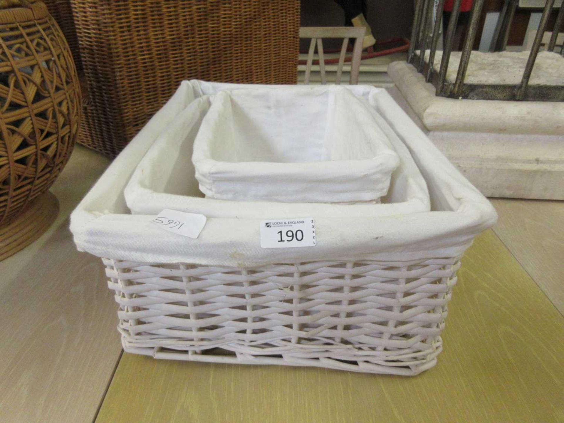 A set of three graduating cream painted wicker baskets with liners (John Lewis 'Woodluv' series)