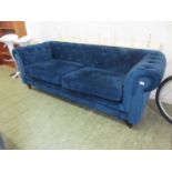 A modern Chesterfield sofa upholstered in a cut deep blue fabric