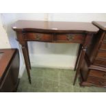 A reproduction mahogany serpentine fronted side table with two drawers on fluted legs