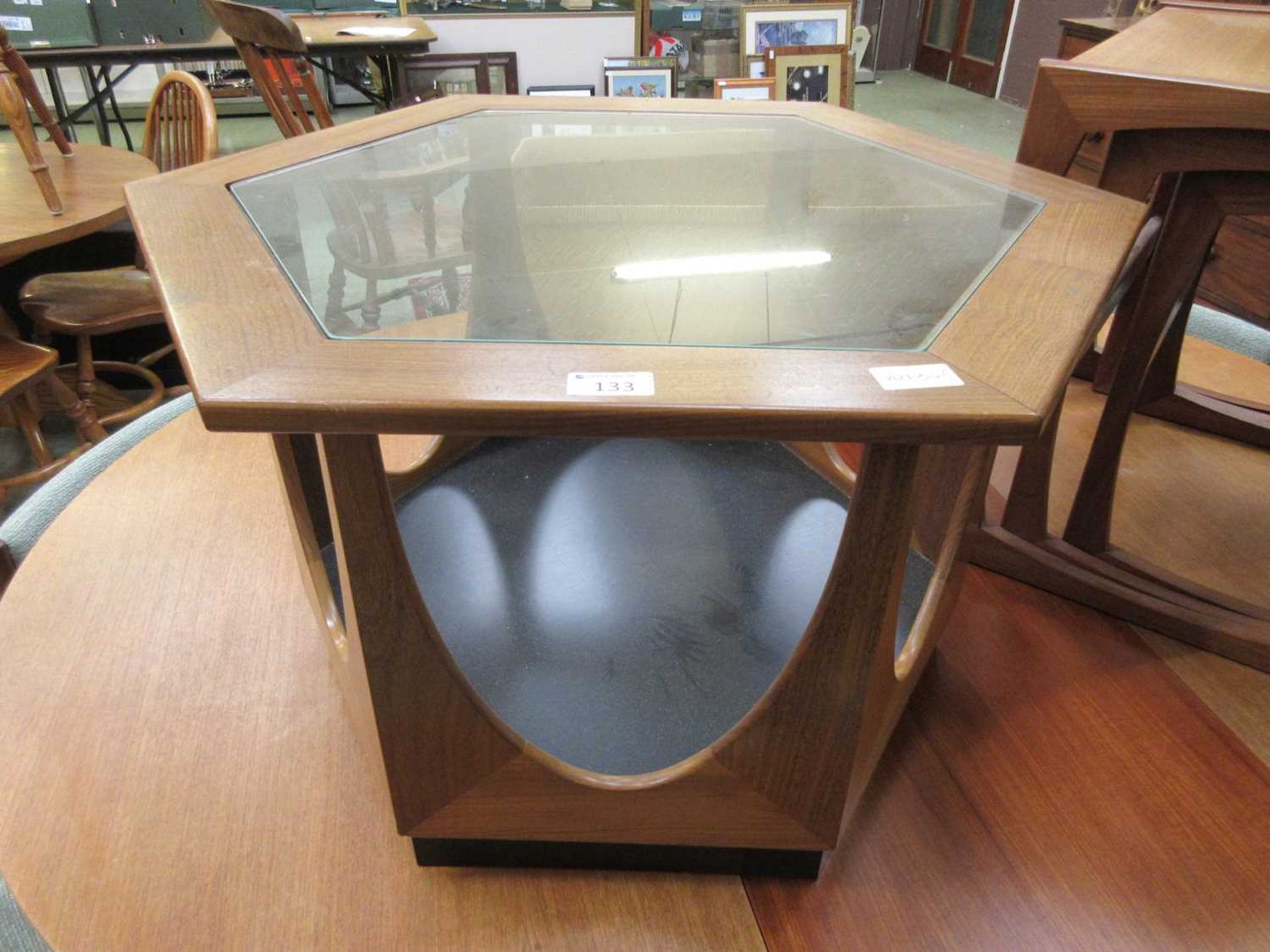 A mid-20th century teak hexagonal occasional table with glass top and under tier