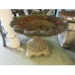 A composite stone bird bath with shell basin