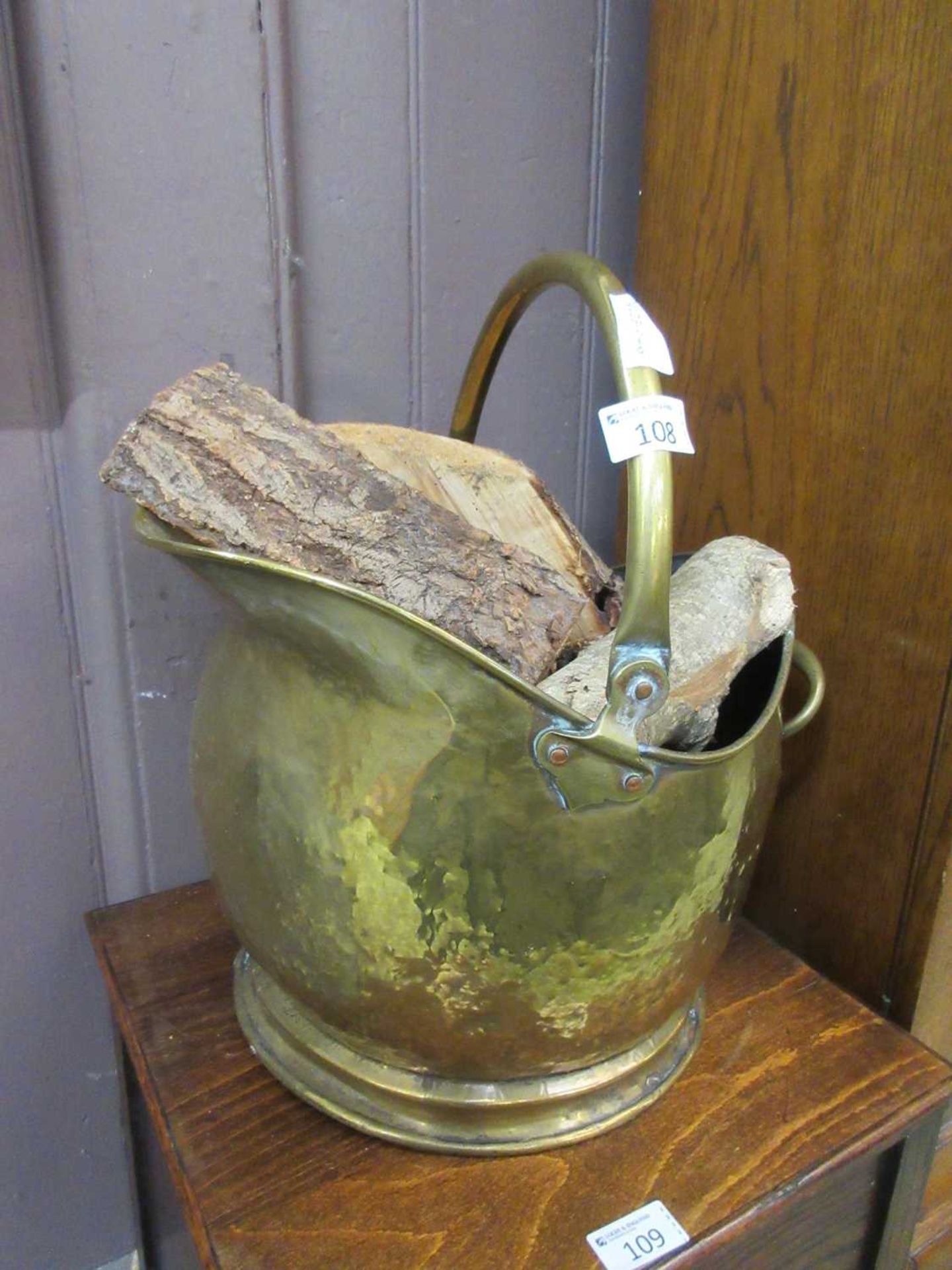 A hammered brass coal scuttle containing wood