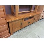 A modern oak TV stand having single drawer flanked by cupboard doors