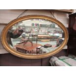 An ornate gilt framed oval bevelled glass mirror